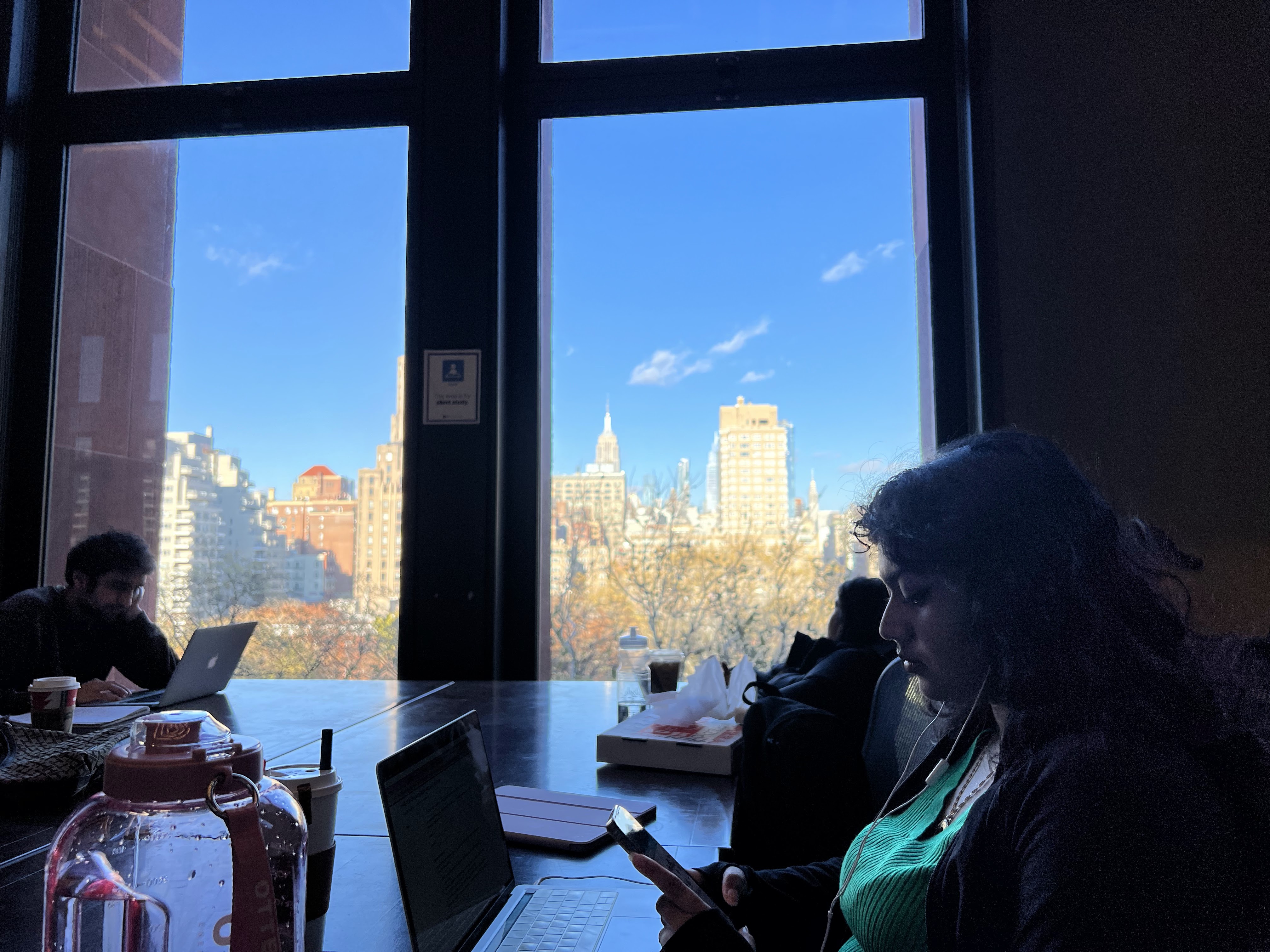 Students at a study table overlooking the New York skyline.